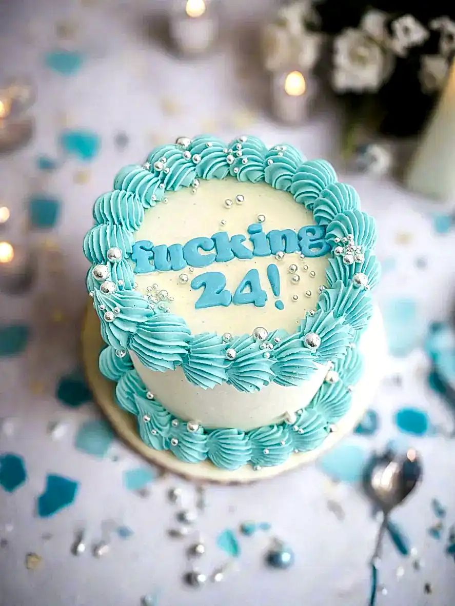 mini cake with fucking 24 words on top in baby blue, finished with shiny silver sprinkles